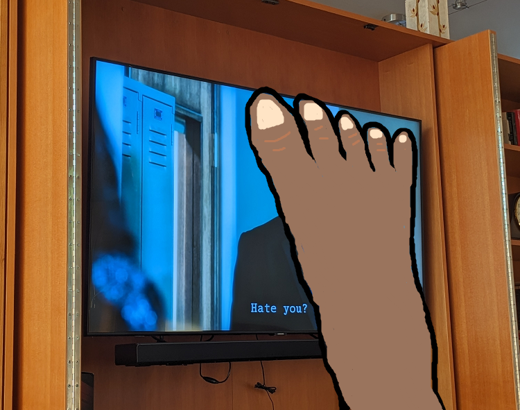 Photo of a mounted television where Pretty Little Liars is playing, with the scene onscreen of Ezra saying to Aria, "Hate you?" On top of the photo, a light brown foot has been crudely drawn in Microsoft Paint, lifted up to block out Ezra's face.