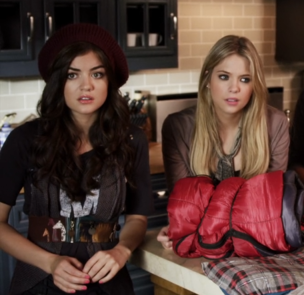 Close-up of Aria and Hanna in Spencer’s kitchen. The focus is on Aria; she is wearing the same outfit as in the last photo but now with a maroon beanie.