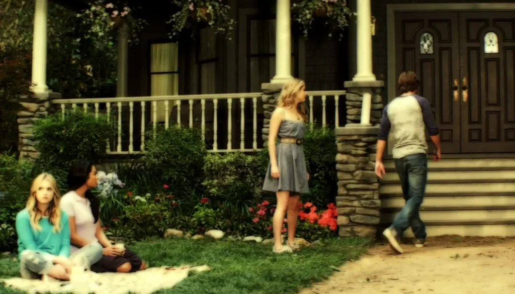 Wide shot of Alison talking to Jason outside their house while he storms off angrily, while Hanna and Emily sit on a picnic blanket on the DiLaurentis yard. We can now see that Ali’s gray dress goes down just above her knees and is belted.