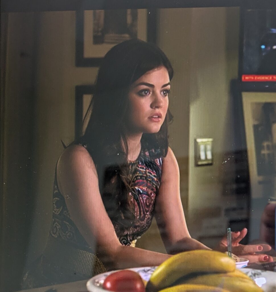 Aria also seated at the kitchen counter, wearing a sleeveless dress with colorful paisley patterns over a black background
