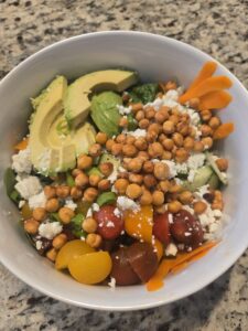 A salad with avocados, greens, tomatoes, carrots, feta cheese, and air fryer-roasted chickpeas on top
