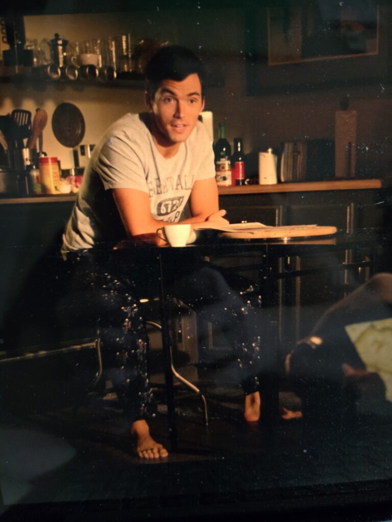 Ezra sitting down talking wearing pajama pants and shirt with his feet out! gross